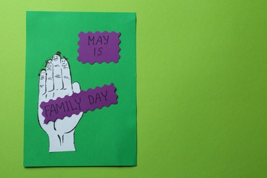 Photo of Paper cards with words Family Day and hand cutout on light green background, top view. Space for text