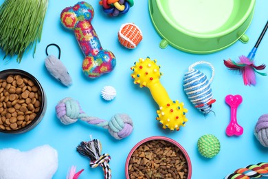 Flat lay composition with different pet toys and feeding bowls on light blue background