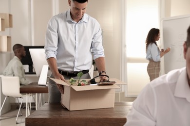 Photo of New coworker unpacking box with personal items at workplace in office