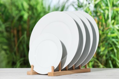 Photo of Many clean plates on white table against blurred background