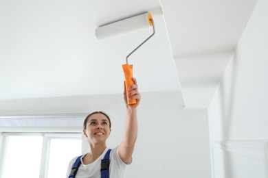 Worker painting ceiling with white dye indoors