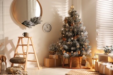 Beautiful decorated Christmas tree and gift boxes in festive room interior