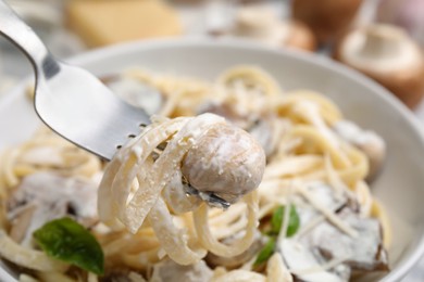 Photo of Eating delicious pasta with mushrooms at table, closeup