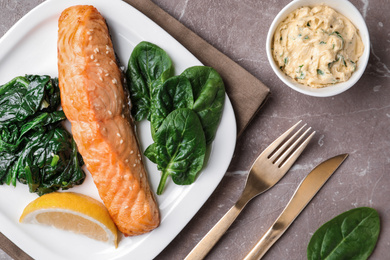 Tasty salmon with spinach and lemon served on marble table, flat lay