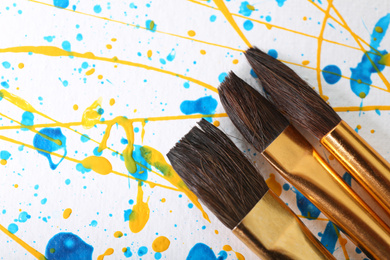 Photo of Brushes on canvas with colorful paint splashes, closeup. Art and creativity