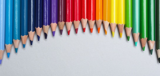 Colorful pencils on light background, flat lay. Space for text