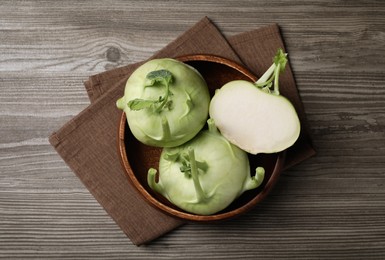 Whole and cut kohlrabi plants on wooden table, top view