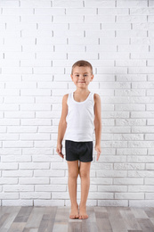 Photo of Cute little boy in underwear near white brick wall
