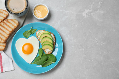 Romantic breakfast with heart shaped fried egg served on light grey table, flat lay. Space for text