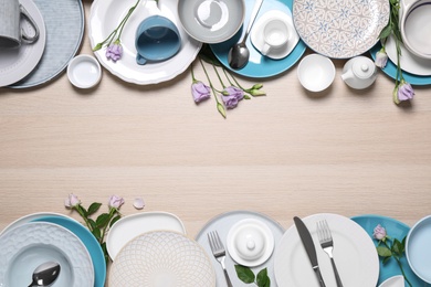 Flat lay composition with beautiful dishware and flowers on wooden table. Space for text