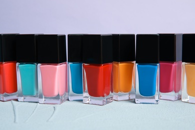 Bright nail polishes on table against color background