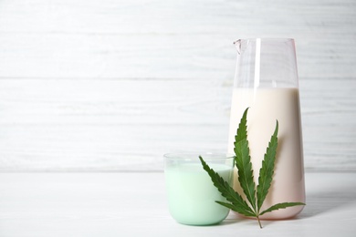 Glass and jug with hemp milk on white table
