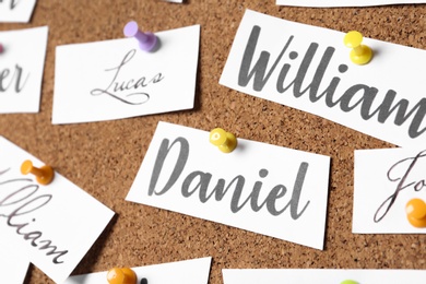 Paper pieces with baby names on cork board, closeup