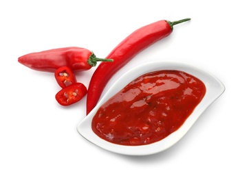 Gravy boat with spicy chili sauce and fresh pepper on white background, top view