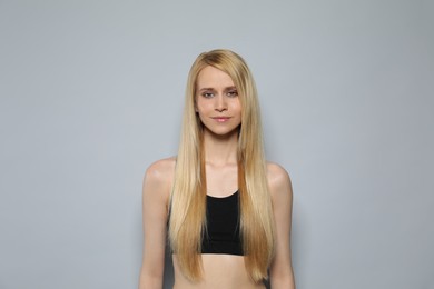 Beautiful young woman with long straight hair on grey background