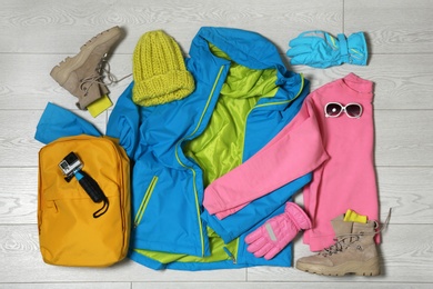 Set of warm clothes and action camera on wooden background, flat lay. Winter vacation