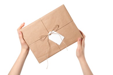 Woman holding parcel wrapped in kraft paper with tag on white background, closeup
