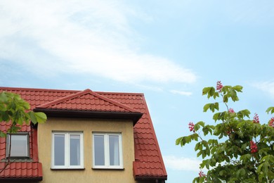 Photo of Beautiful house with red roof against blue sky, low angle view