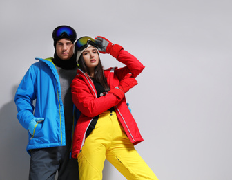 Couple wearing stylish winter sport clothes on light grey background. Space for text
