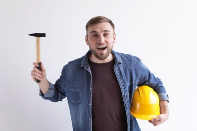 Happy young working man with hammer and hardhat on white background