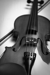 Image of Beautiful violin and bow on table, closeup. Black and white tone