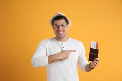 Male tourist holding passport with ticket on yellow background