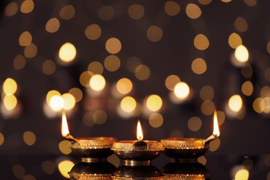 Lit diyas on table against blurred lights. Diwali lamps