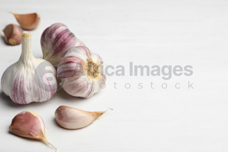 Fresh organic garlic on white wooden table. Space for text