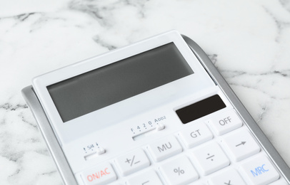 Calculator on white marble background, closeup. Tax accounting concept
