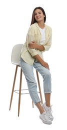 Beautiful young woman sitting on stool against white background