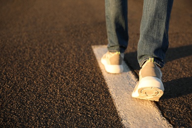 Man walking along white line on road, closeup with space for text. Way concept
