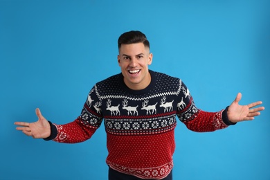 Excited man in Christmas sweater on blue background