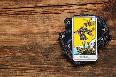 The Fool and other tarot cards on wooden table, flat lay. Space for text