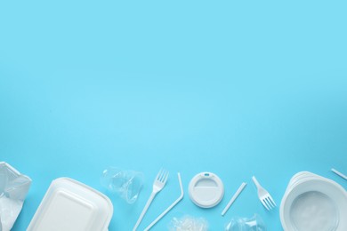 Plastic dishware on light blue background, flat lay. Space for text