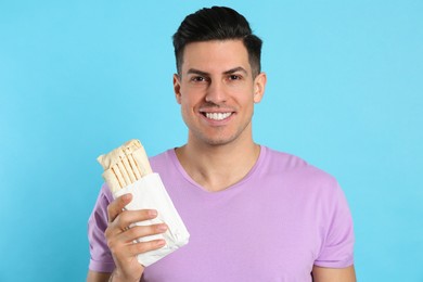 Photo of Man with delicious shawarma on turquoise background