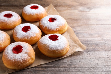 Hanukkah doughnuts with jelly and sugar powder on wooden table, closeup