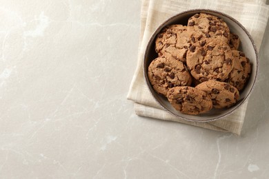 Delicious chocolate chip cookies in bowl on light grey table, top view. Space for text