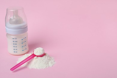 Powdered infant formula with scoop and feeding bottle on pink background, space for text. Baby milk