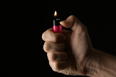 Man holding pink lighter on black background, closeup
