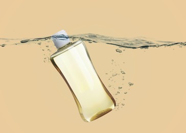 Bottle of baby oil in water against beige background