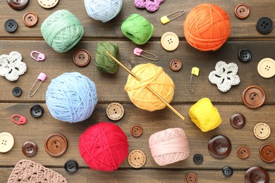 Photo of Flat lay composition with clews of colorful knitting threads and crochet hook on wooden table