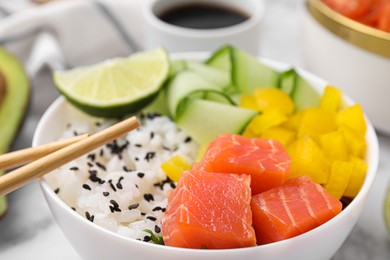 Photo of Delicious poke bowl with salmon, lime and vegetables on table, closeup