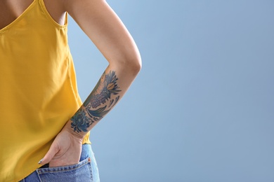Young woman with tattoo on color background, closeup. Space for text