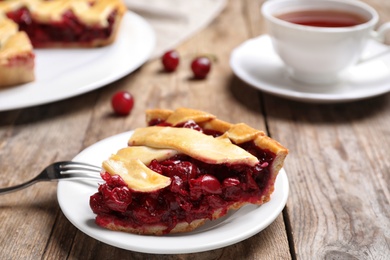 Slice of delicious fresh cherry pie on wooden table, closeup