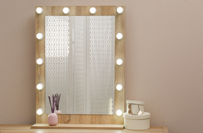 Stylish mirror with light bulbs near beige wall