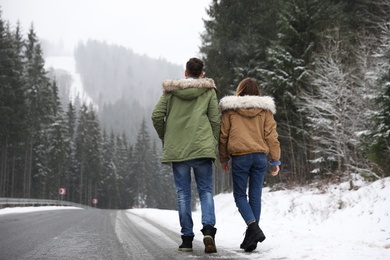 Couple walking near snowy forest. Winter vacation