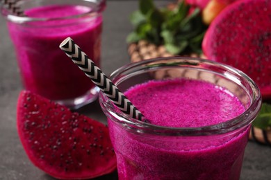 Glass of tasty pitahaya smoothie with straw on table, closeup view