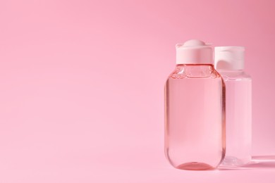 Bottles of micellar water on pink background. Space for text