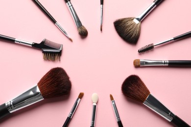 Frame of different makeup brushes on pink background, flat lay. Space for text