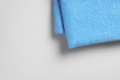 Soft folded light blue towel on light grey background, top view. Space for text